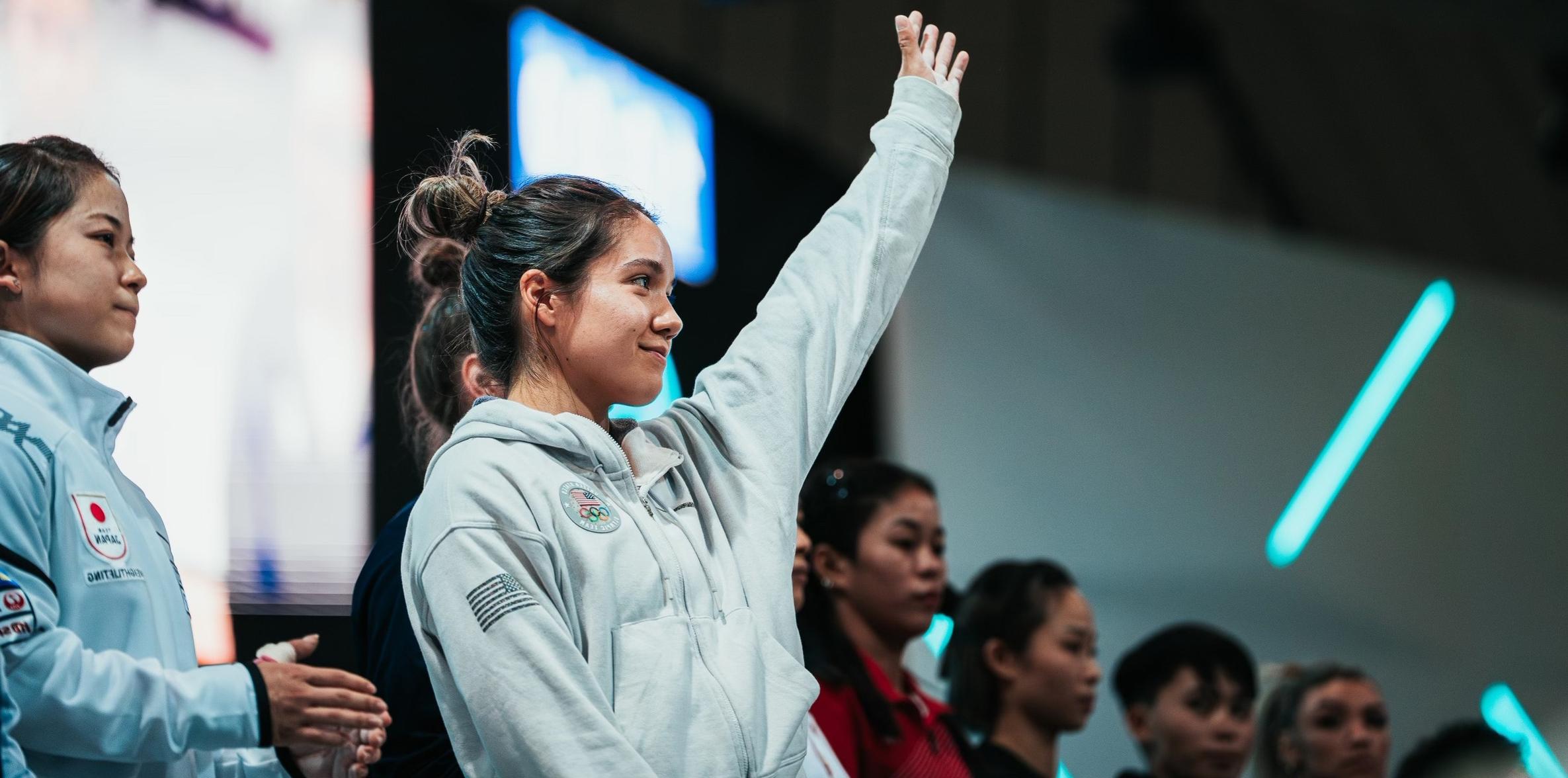 Jourdan Delacruz standing with her arm up waving